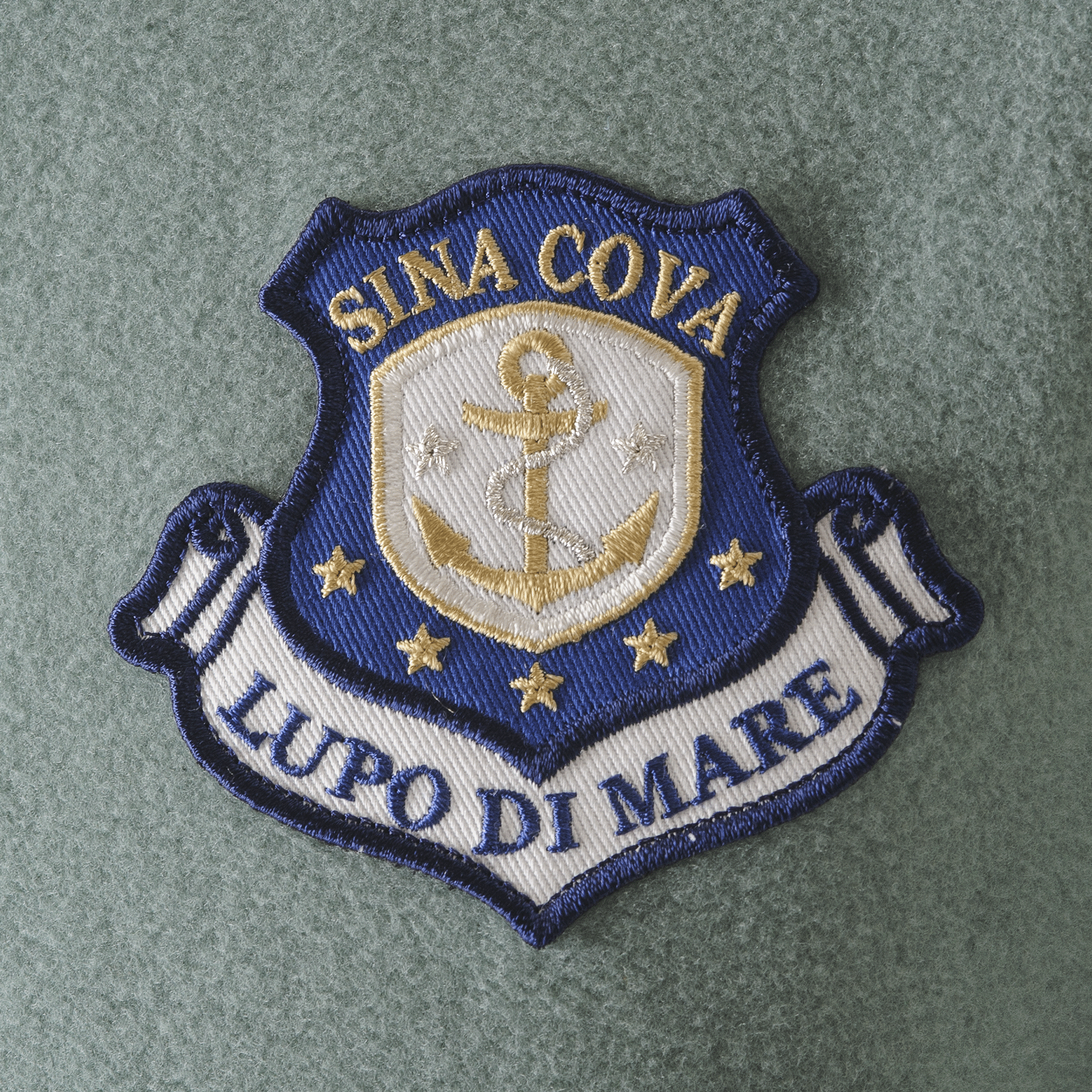 【公式】シナコバ (SINA COVA) ハイネックプルオーバー ユニセックス(男女兼用) 23210070 カーキのワッペン部分